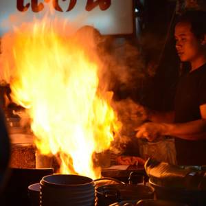 homme cuisinant un wok en feu